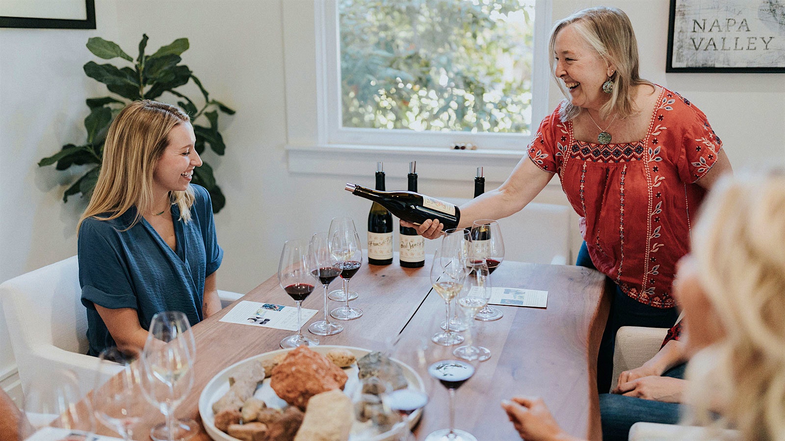 A woman pours a glass of red wine for a guest at Lang & Reed Spring House.